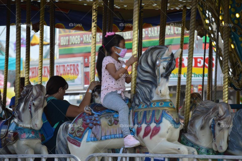 girl riding carousel during covid-19