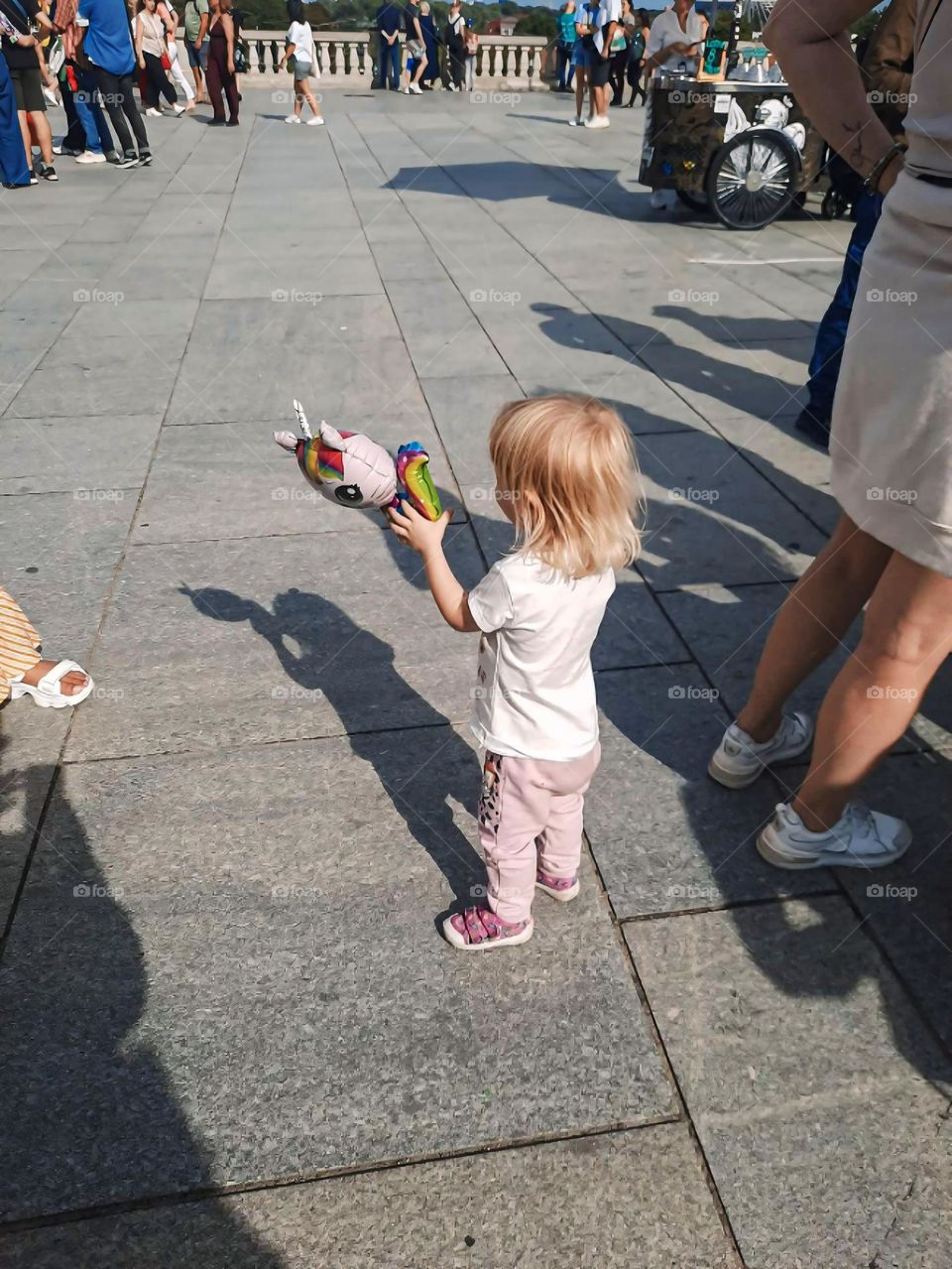Child Holding a Toy in Public Square
