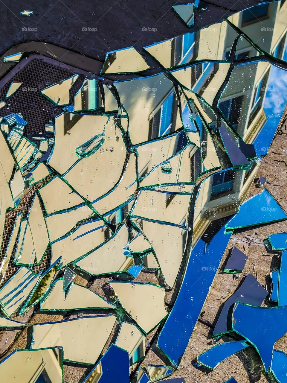 Broken mirror on the sidewalk in San Francisco California, with the reflection of the building above forming an abstract geometric pattern 