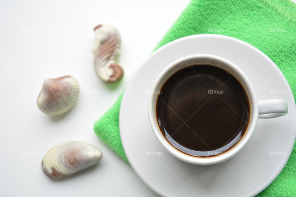 coffee mug and chocolate candies on a white background top view