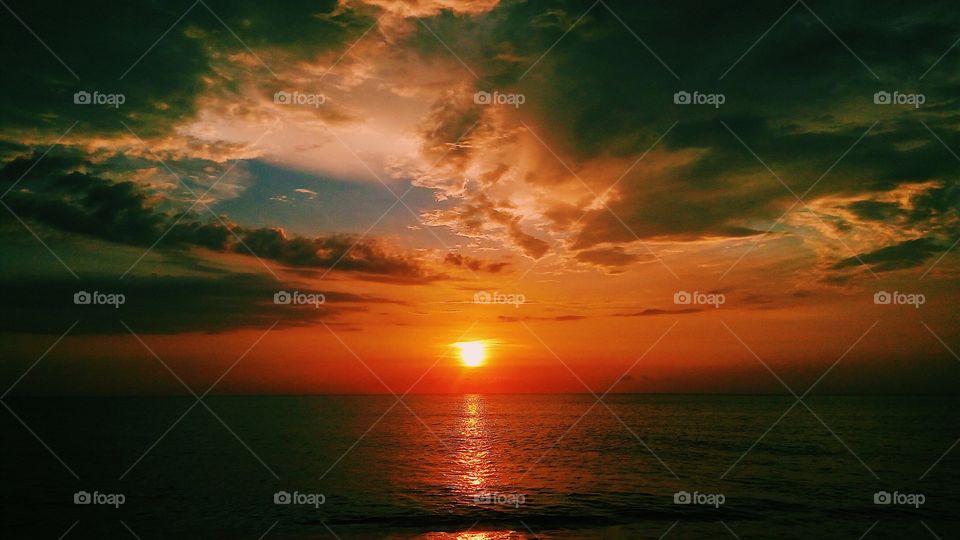 A relaxing view of the orange sunset against the blue sky and sea.