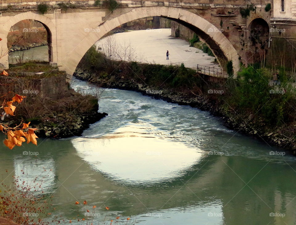 framed person by the bridge arches and their reflection into the water