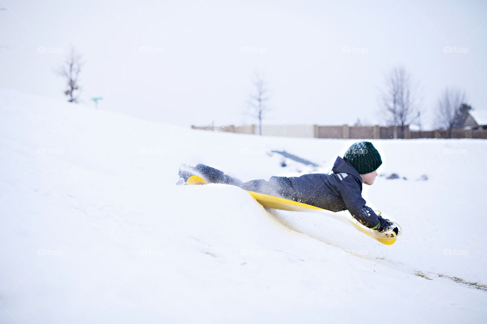 Kid sledding down a hill in winter 