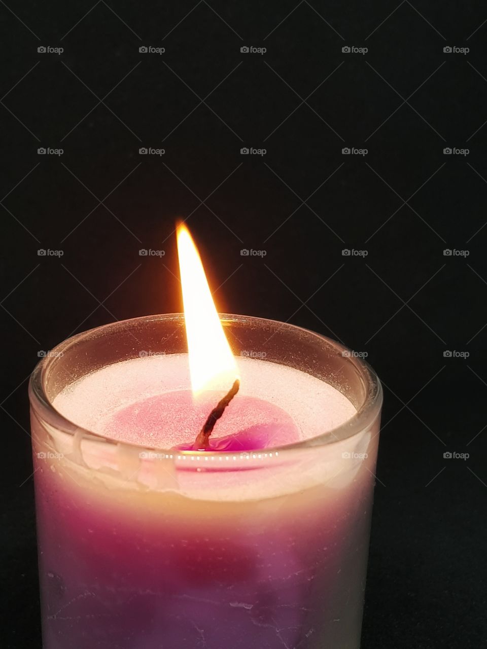 Candlelight in the dark. The outer side of candle is glass and texture colour is pink, white pink.