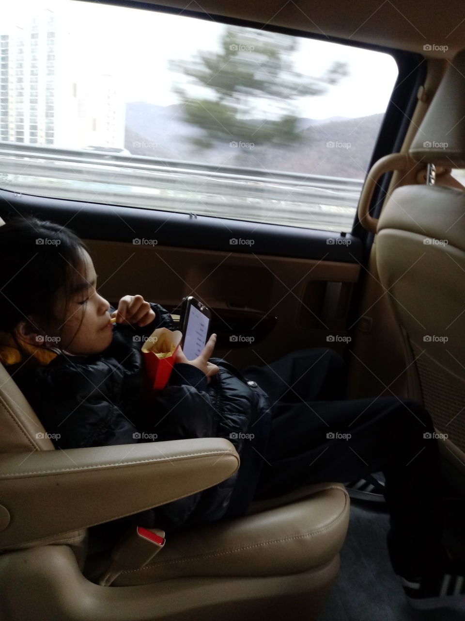 eating something to feed the hunger from the long hours of travel.  she loves french fries so she really enjoy it so much. with it, shes not getting bored anymore.