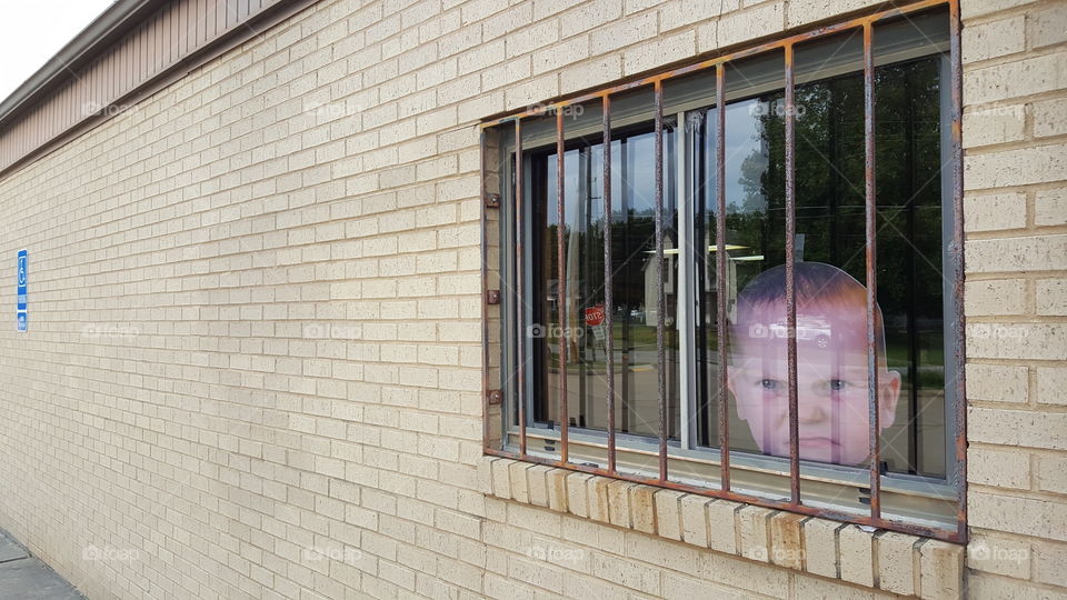 Big Baby Head Behind Window Bars