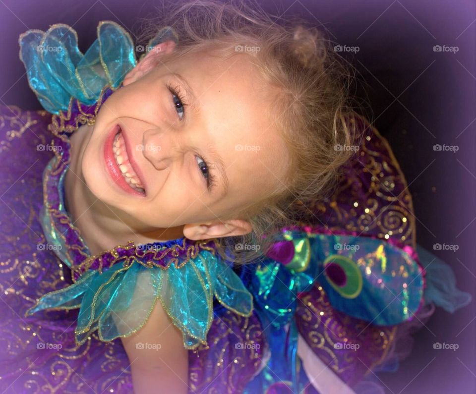 Big Smile, Little Girl. Little girl, wearing a peacock princess dress, smiling big for the camera. 