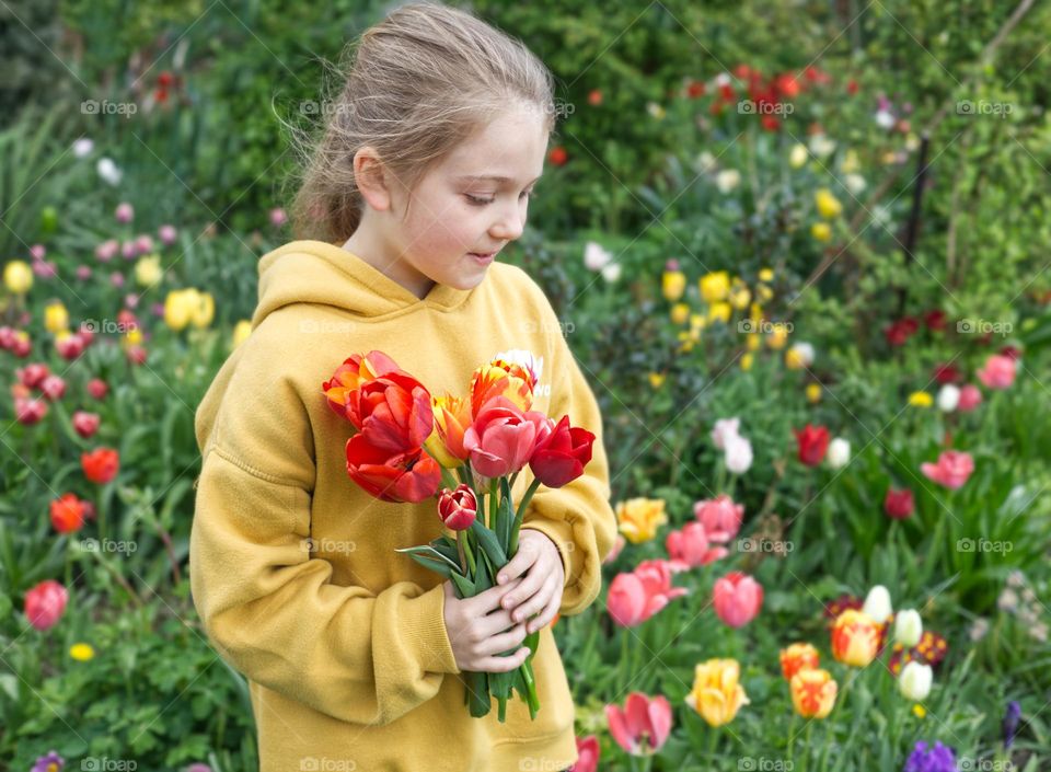 Girl in the garden holding beautiful tulip flowers.