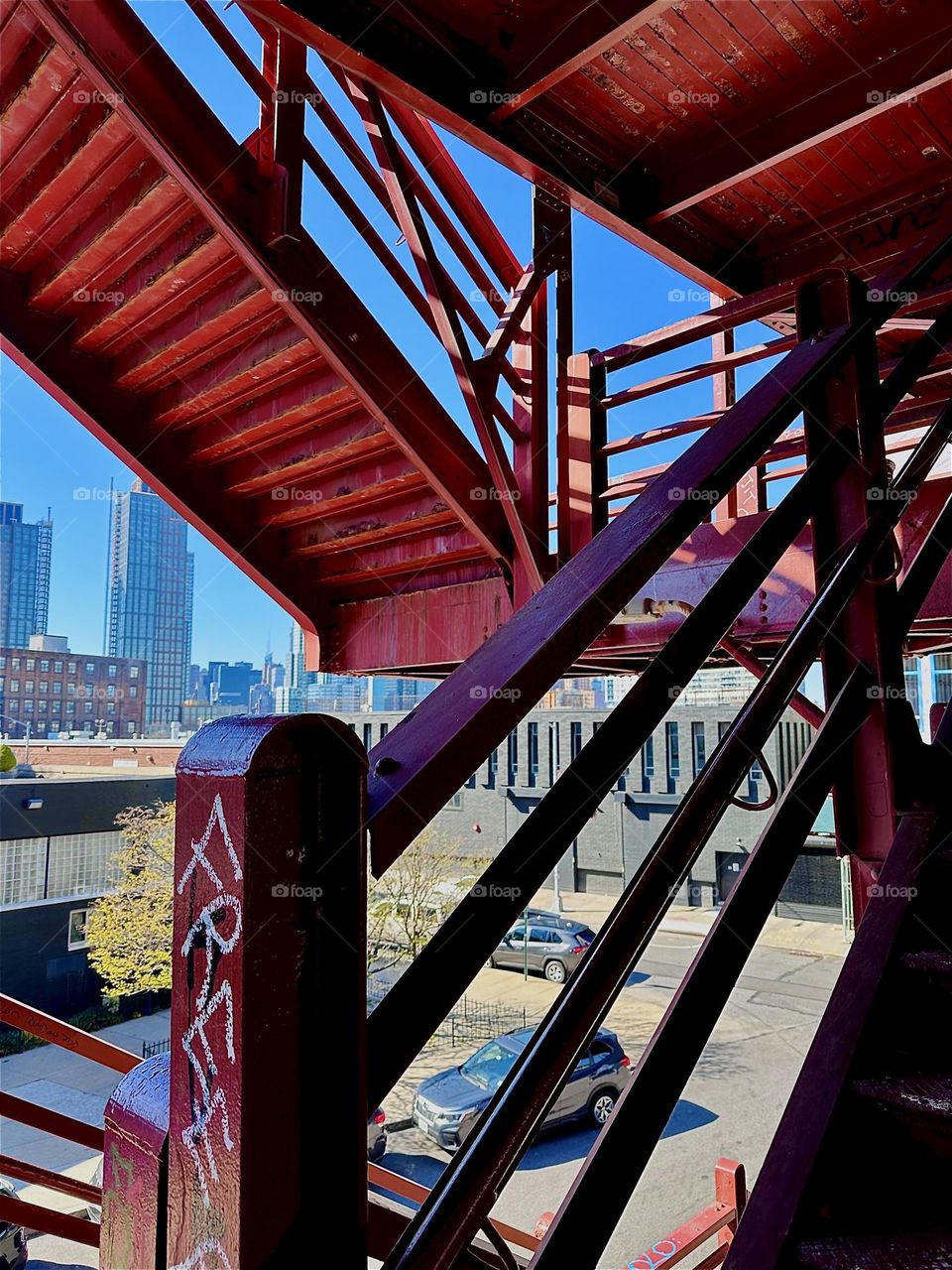 This is the red metal staircase of the “Pulaski Bridge” at “Newtown Creek” that connects LIC, Queens to “Greenpoint”, Brooklyn. Its style reminds in many ways of the “Bauhaus” school in “Weimar”, Germany of the 1930s. 2024. Hypnotic Productions