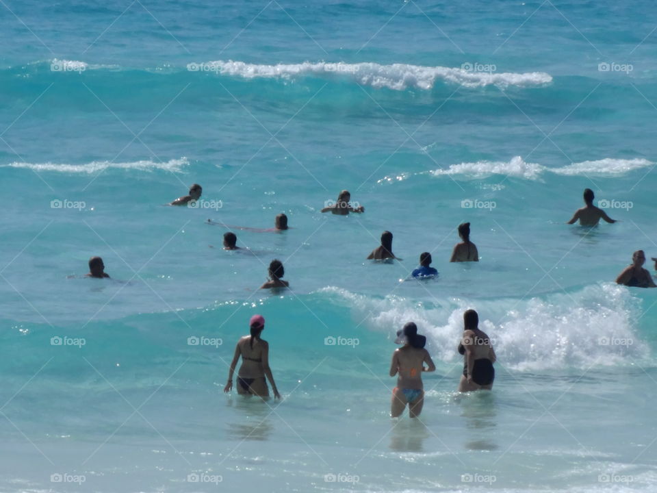People wading in the turquoise ocean water, Cancun Mexico