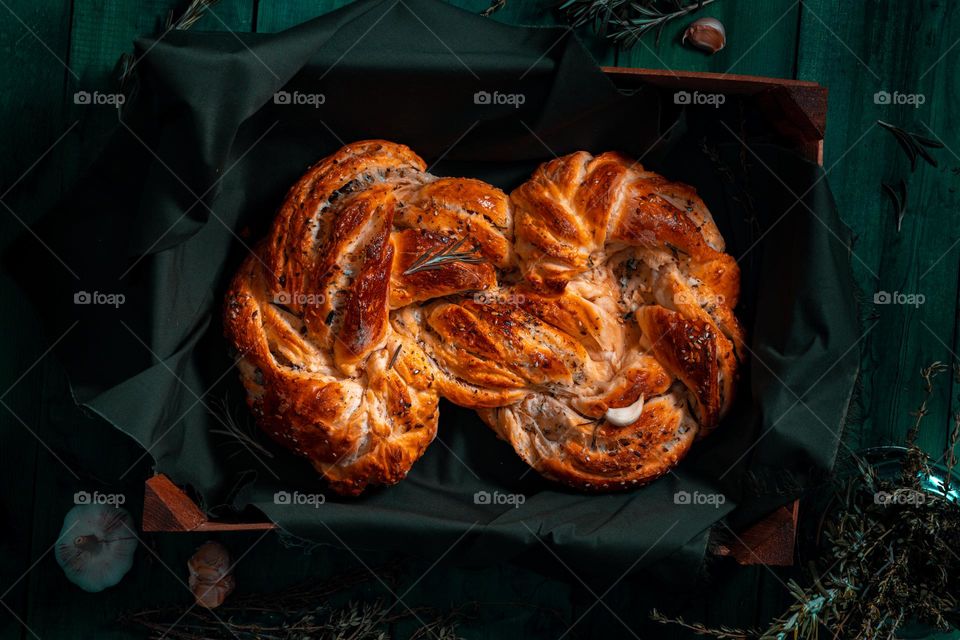 Rosemary twisted loaf bread on a green wooden background, still life, rustic style.