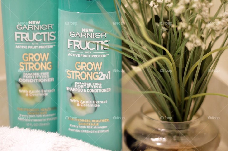 Garnier shampoo and conditioner on a bathroom countertop next to a plant and a white towel
