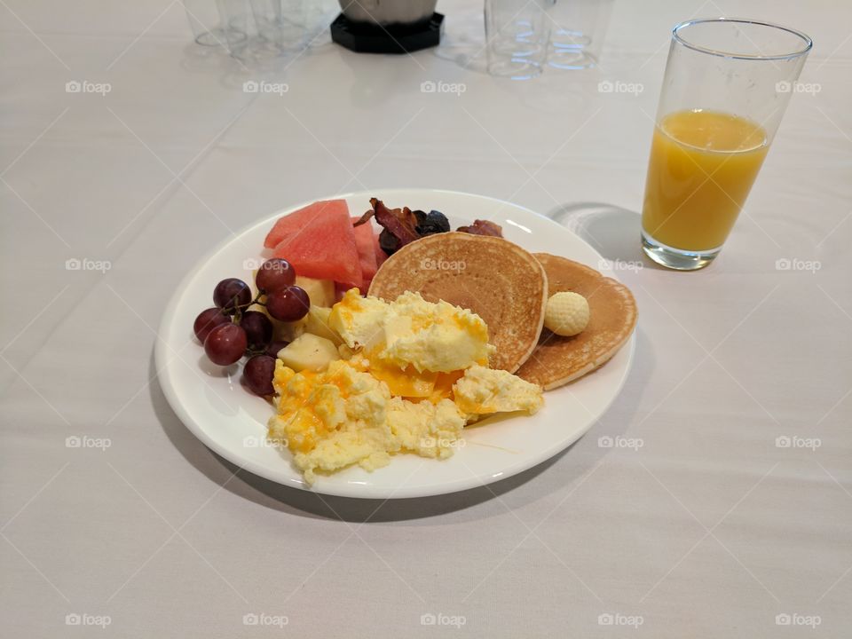 plate of delicious breakfast foods pancakes eggs some fruits and bacon