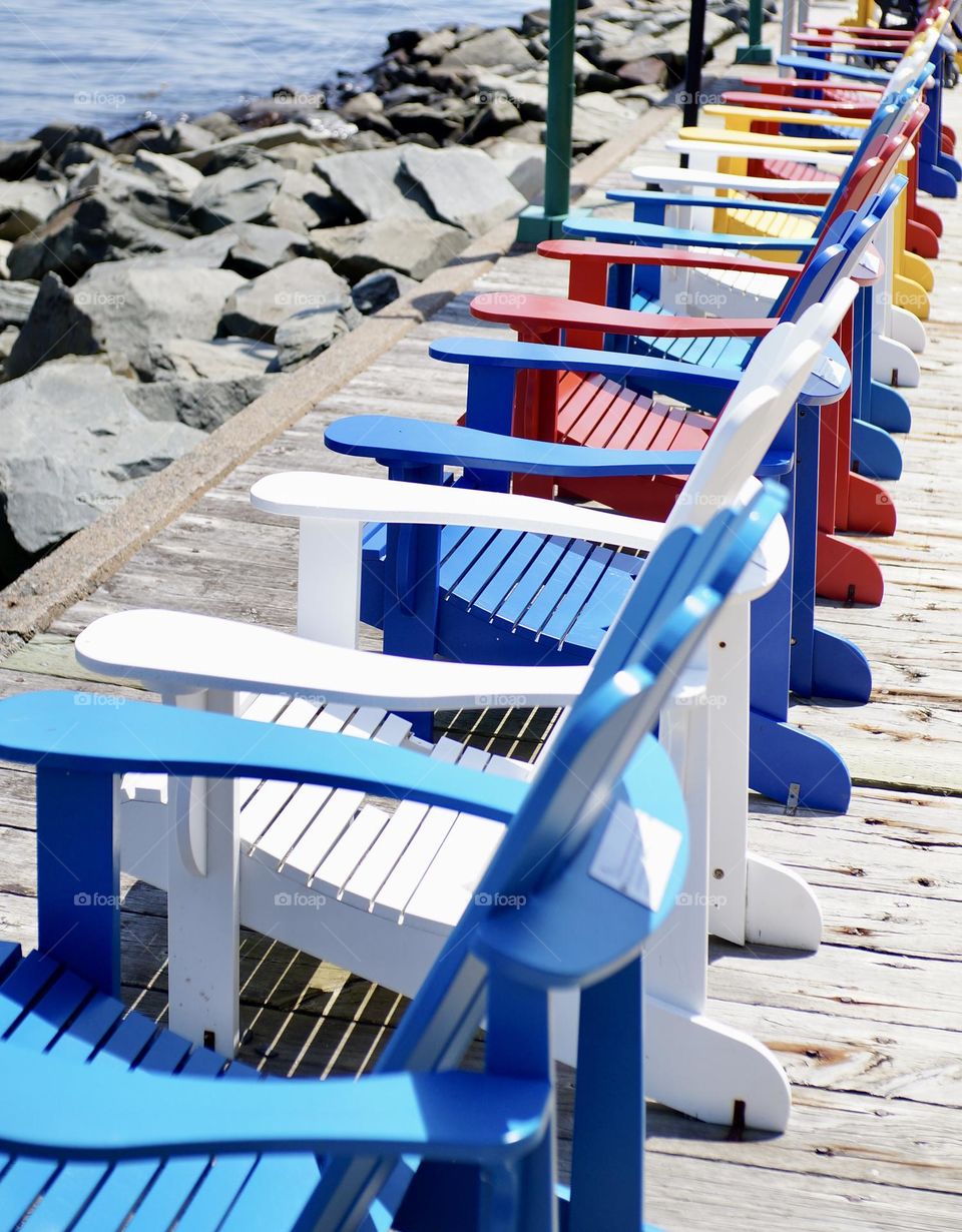 A white Muskoka chair amongst its colourful friends.