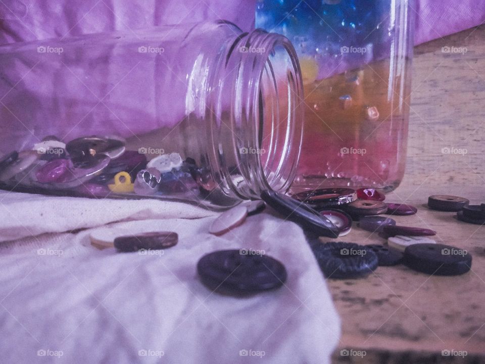 This is a creative and a colourful idea.There is a bottle with a full of colourful marbles and there is a bottle with buttons.Some of bottons are laying on the surface and  however this is very creative and colourful idea..❇️