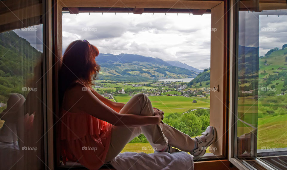 Woman sitting in the window looking at amazing view 