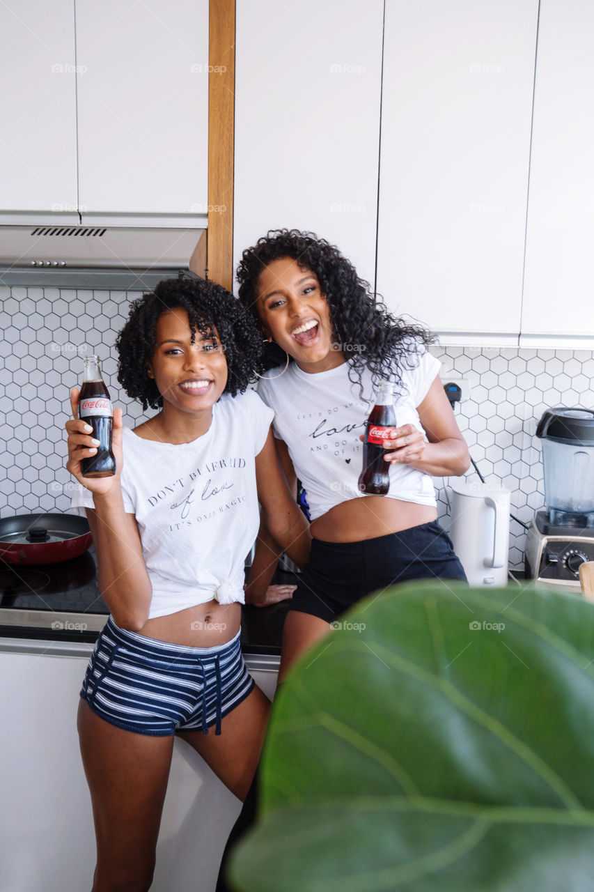 Two friends enjoying drinking Coca Cola during their conversation in the kitchen