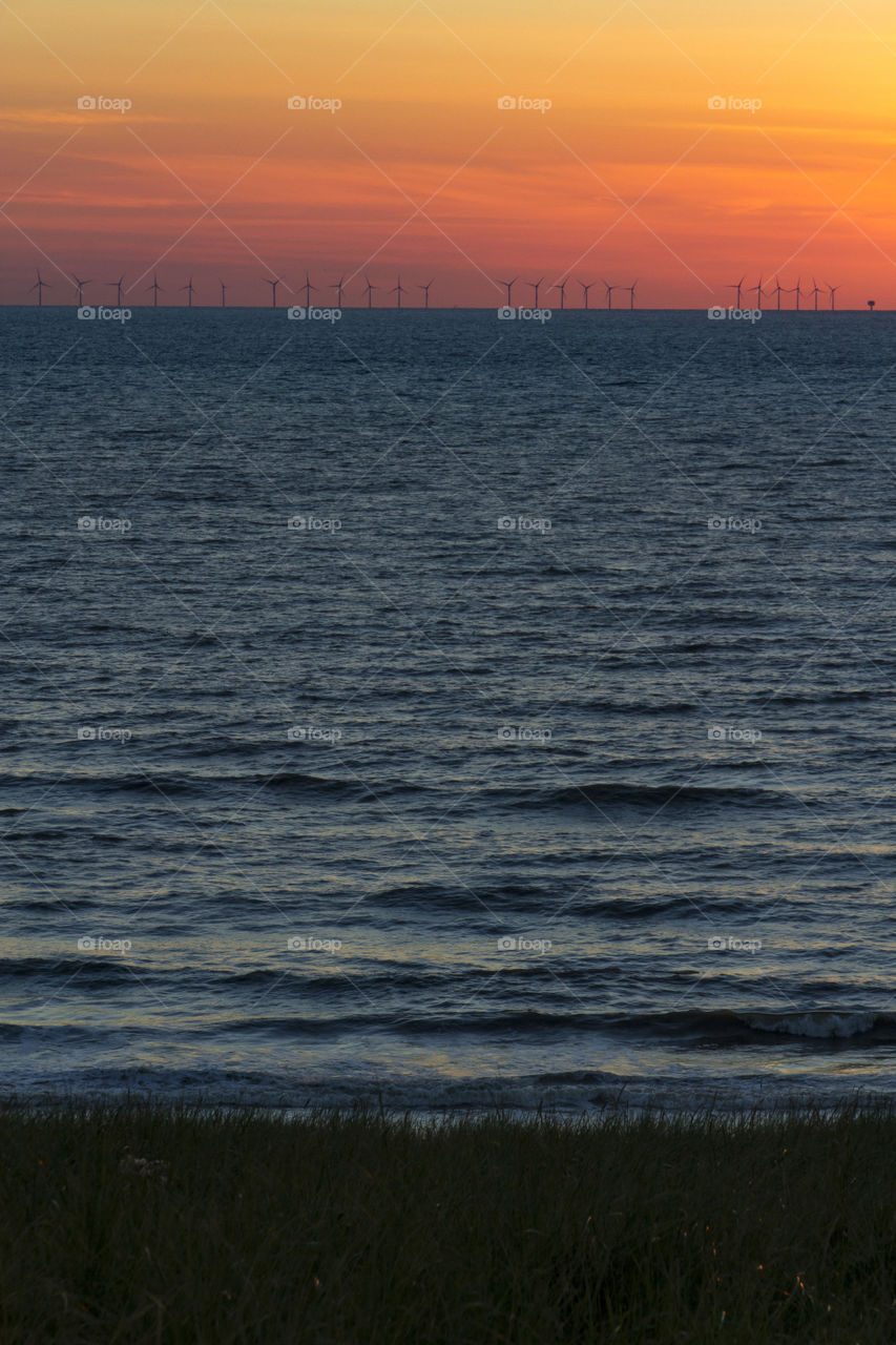 Windmills in the ocean at sunset