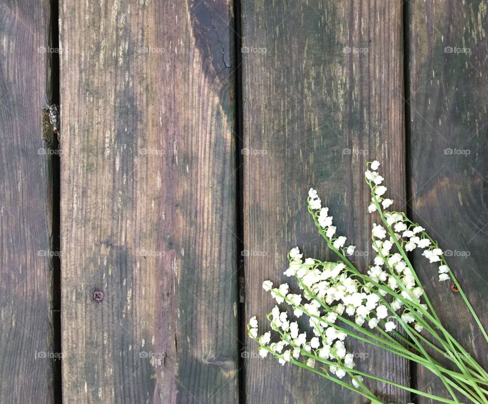 Lily of the valley flat lay on a dark, rustic, wooden surface 