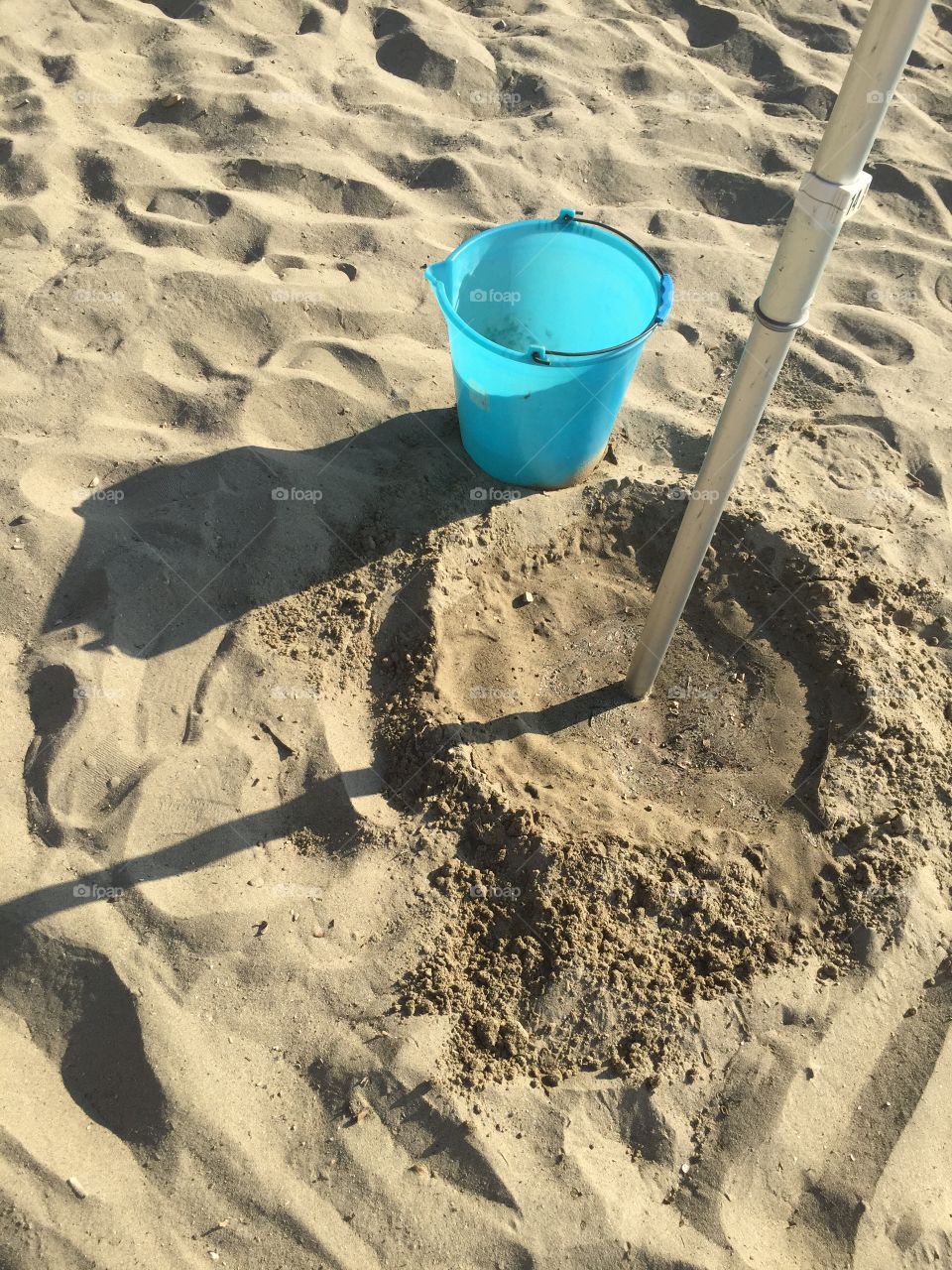 Bucket and umbrella beach pole on the beach 