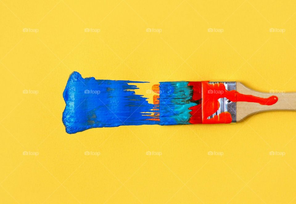 Colorful painted paintbrush on yellow background