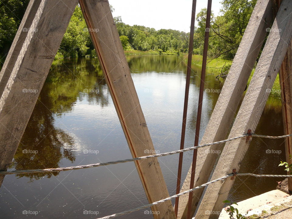 View of reflecting trees on lake from wooden bridge