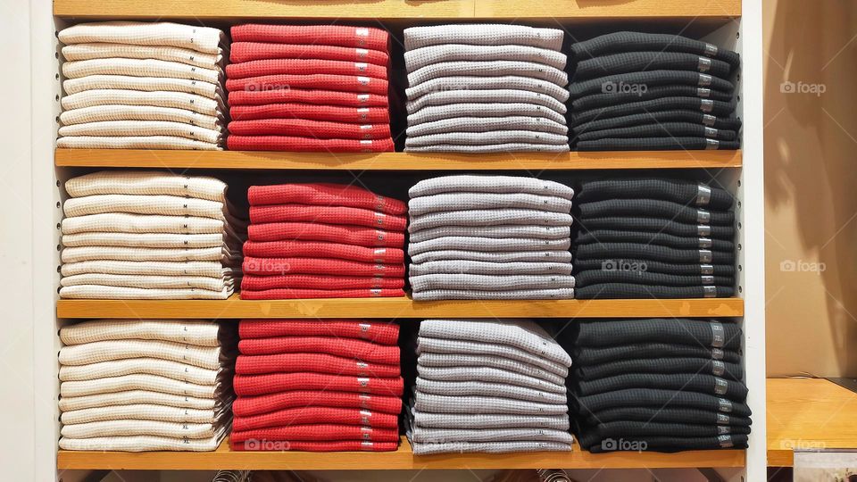 Stack of cloth ready to sell in the shelf at the mall or clothing store.
