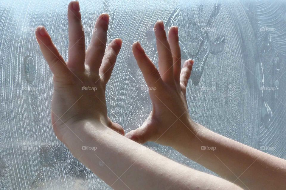 Hands of a child on a soap window