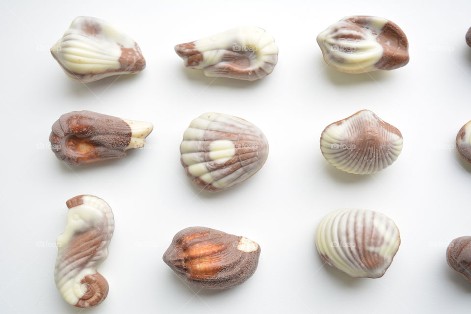 chocolate candies seashells on a white background top view beautiful texture