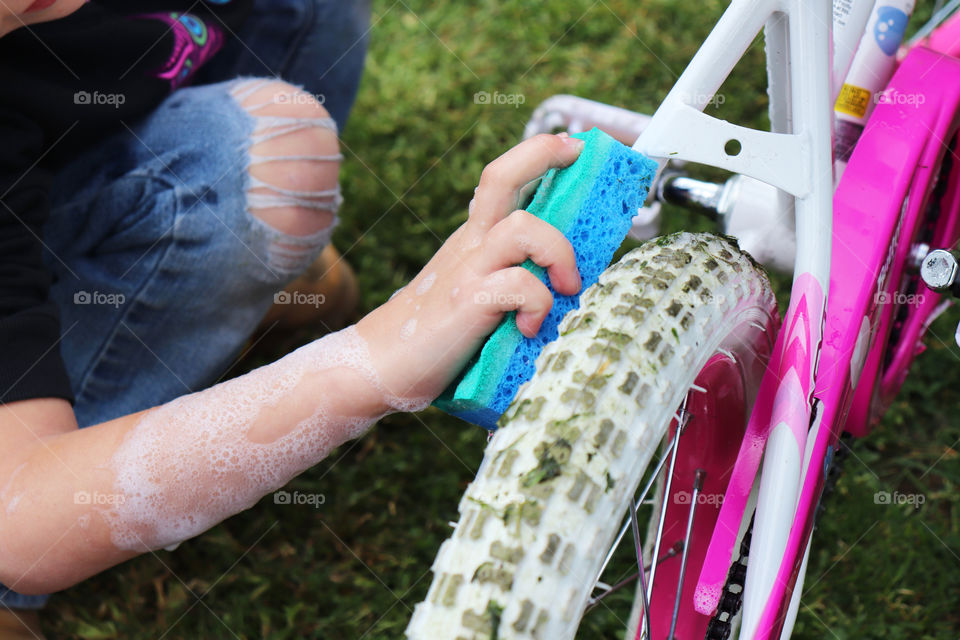 Child cleaning her bike with a sponge