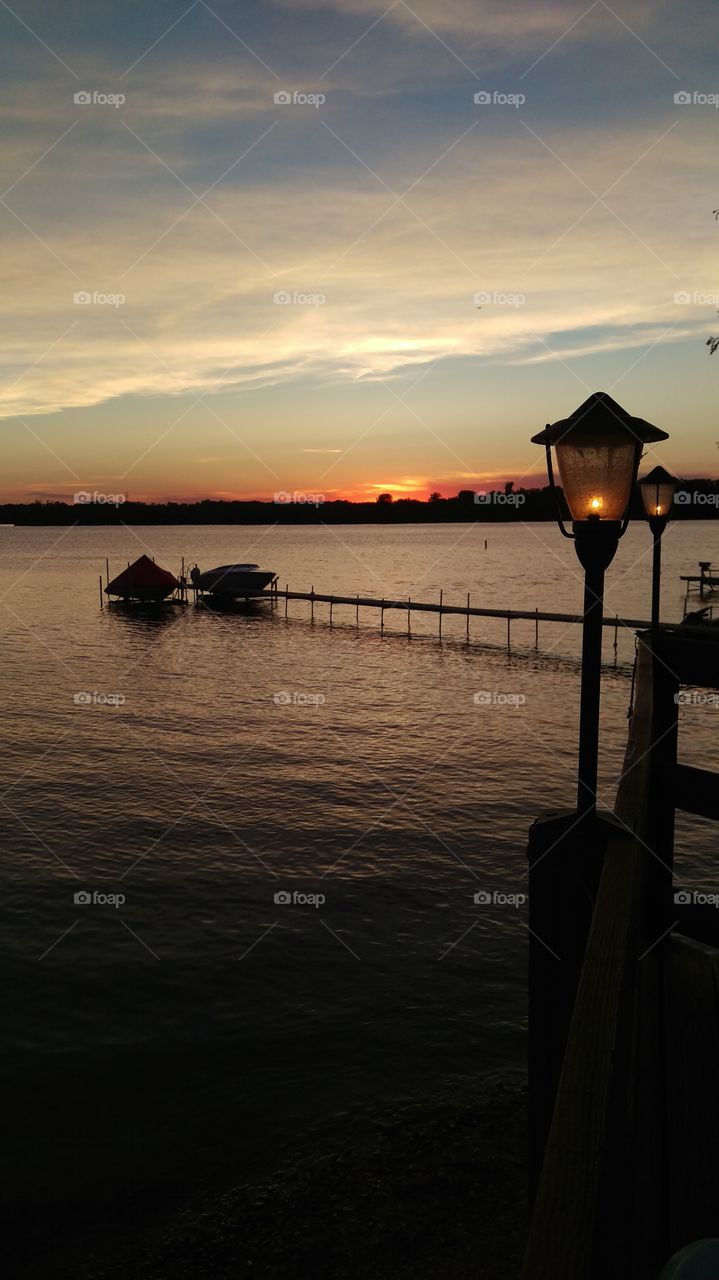 Sunset romance.  a romantic dinner by a lake with a beautiful sunset and lanterns while watching boaters