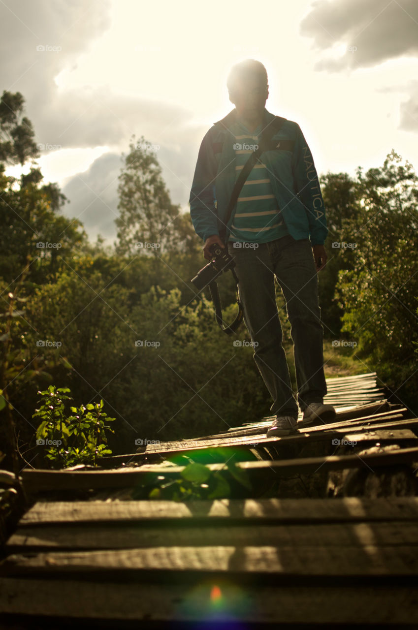 Man photographer walking on a wooden bridge in the forest