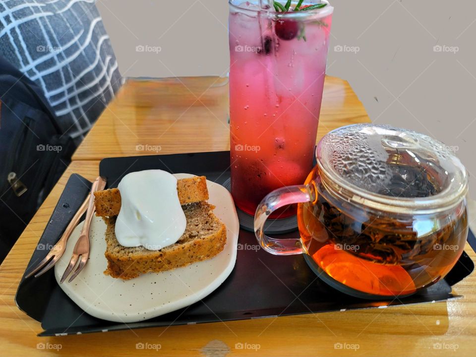 Pound cake with fresh cream, a glass of berry sparkling drink and a pot of black tea