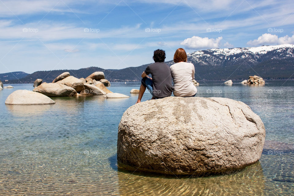Couple sitting on rock in Lake tahoe