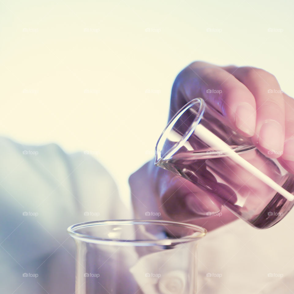 Woman using chemistry and science equipment filled with fluid