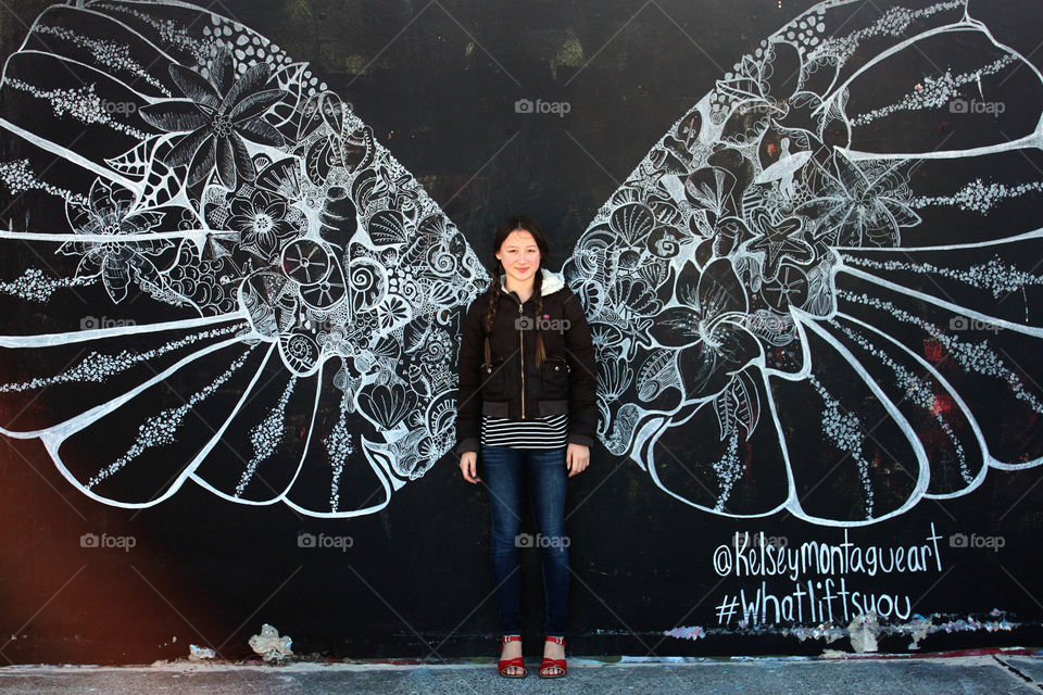 Young woman with wings on blackboard