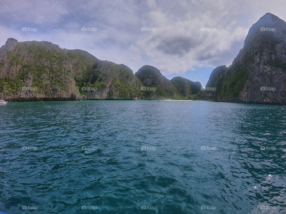 Espléndido paisaje de mar con fondo montañoso y de vegetación abundante en día nublado.