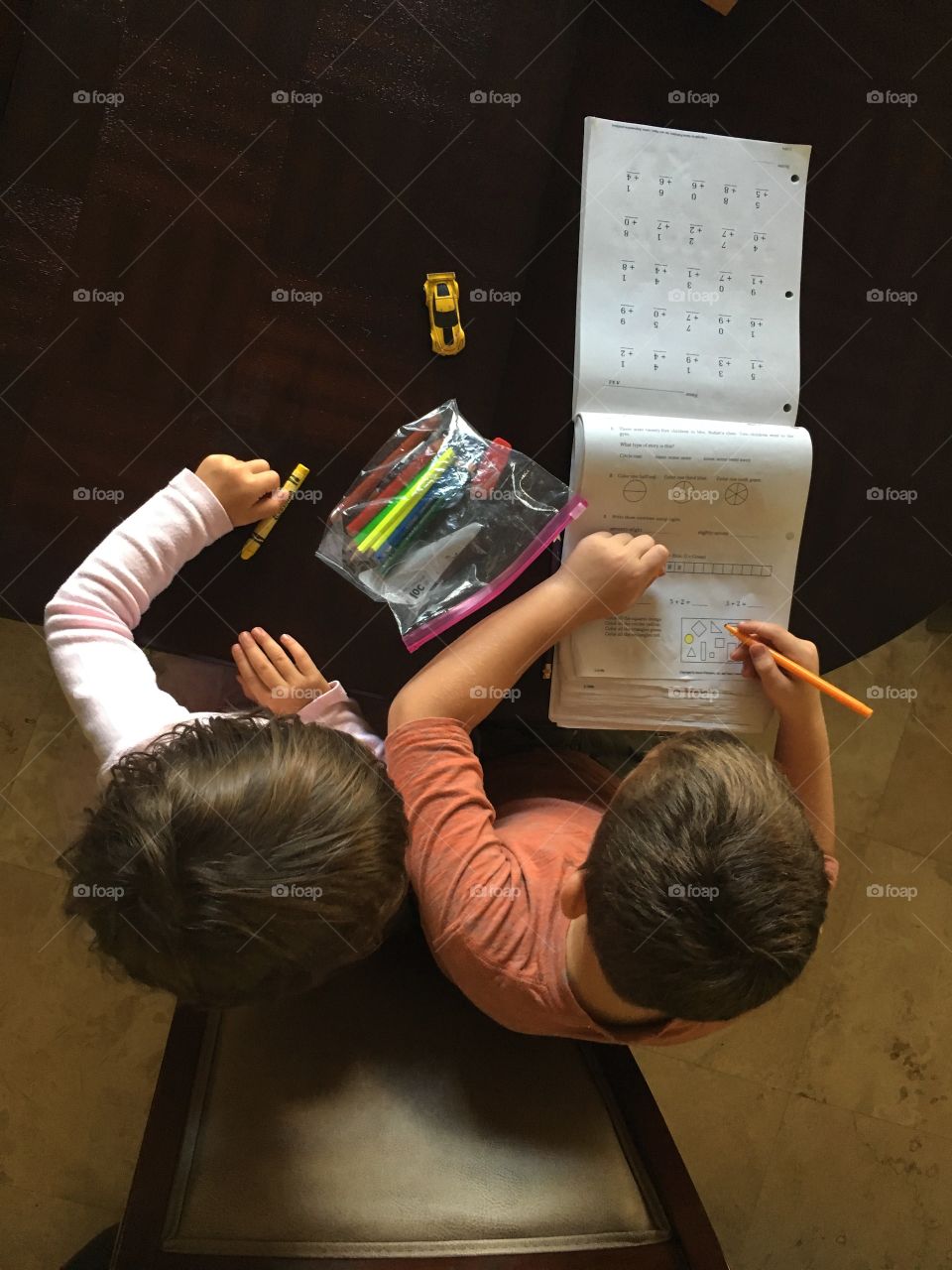 The boy in the picture is doing his Math and graciously let his younger cousin to watch him while at work. So not only he is learning but his little cousin too. 