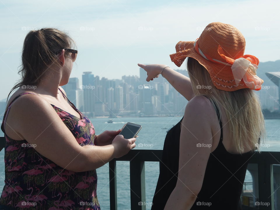 Cityscape, Tourists pointing out to the sunny Hong Kong Skyline.