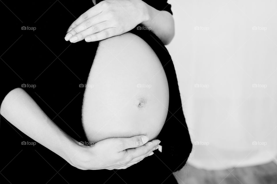 Mid section view of a pregnant woman touching her belly