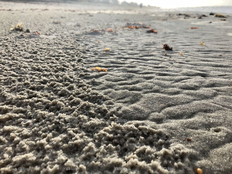 Rain pattern on sand partially washed away by incoming tide