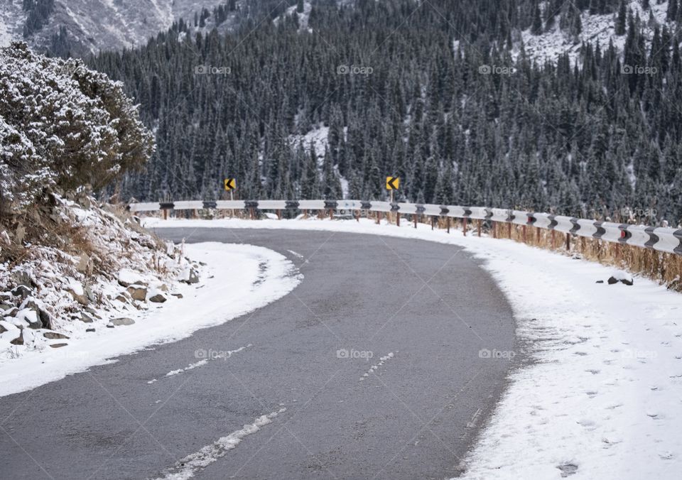 Curve road on beautiful background of snow mountain and pine forest along the way to big Almaty lake , Kazakhstan 
