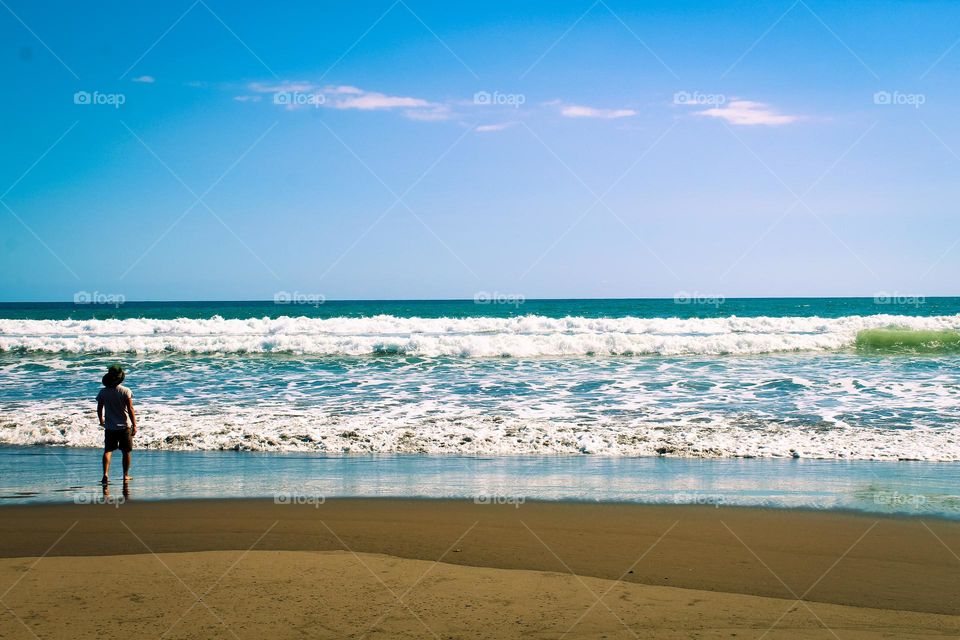 A young man enjoyed himself by the sea watching the big white waves.  Palosecobeach,  Costa Rica