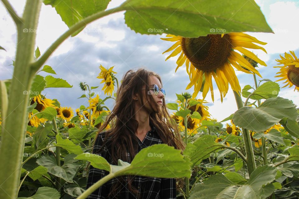the girl is standing in a field of sunflowers