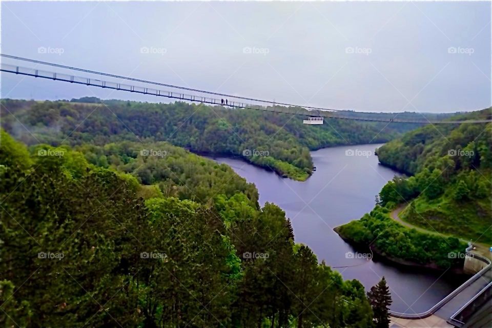 This is the „Rappbode Dam“ with water reservoir and a power plant near „Oberharz“ in „Harz“, „Saxony-Anhalt“ in the former „East Germany“ or „DDR“. An extremely long hanging bridge leads across the reservoir below. 2024. Hypnotic Productions