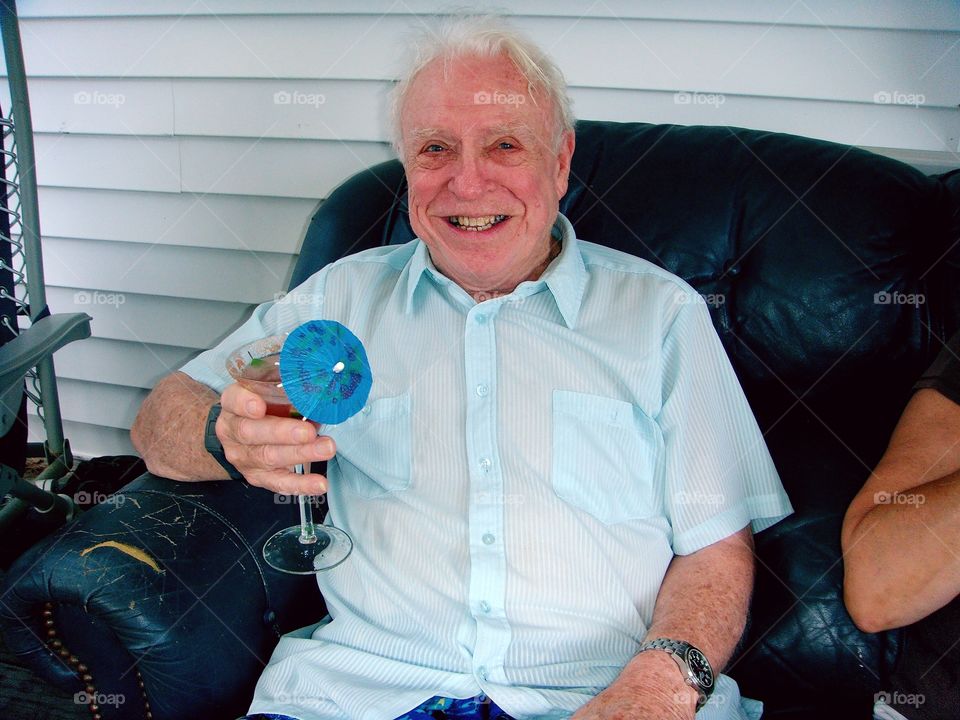 Grandfather elder with martini, smiling.