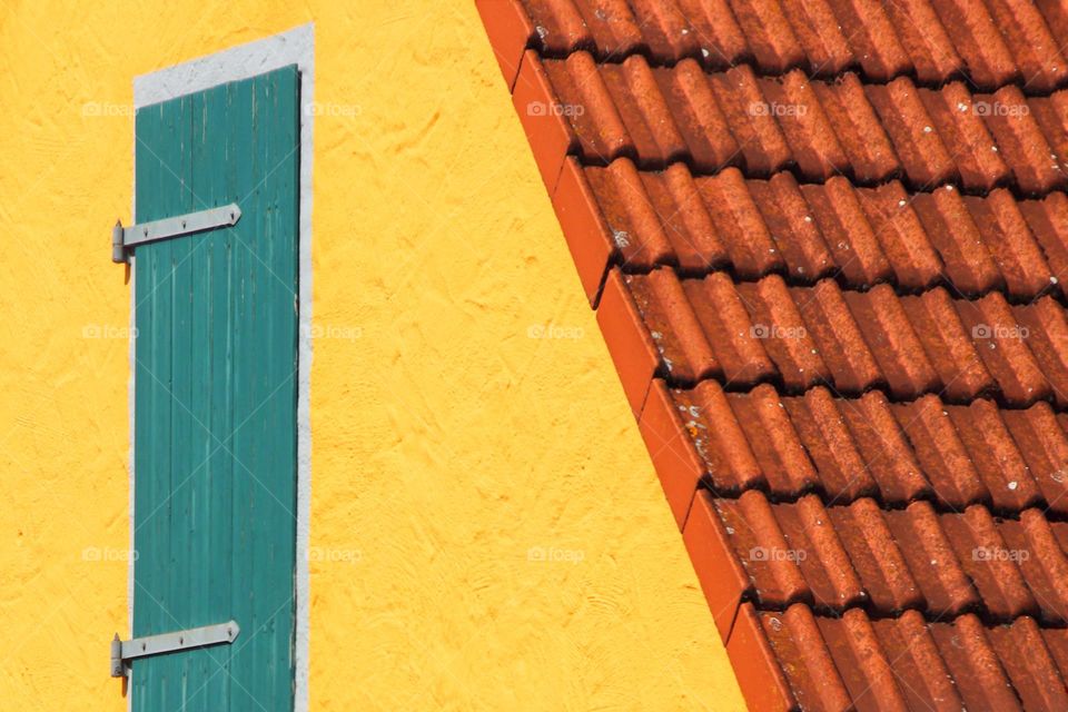 Close-up of a green wooden door on an orange house with red roof tiles