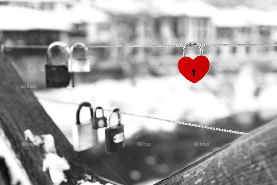 Red color love story (love locks on Episcopal Bridge in Veliko Tarnovo, Bulgaria, background - unfocused winter cityscape)