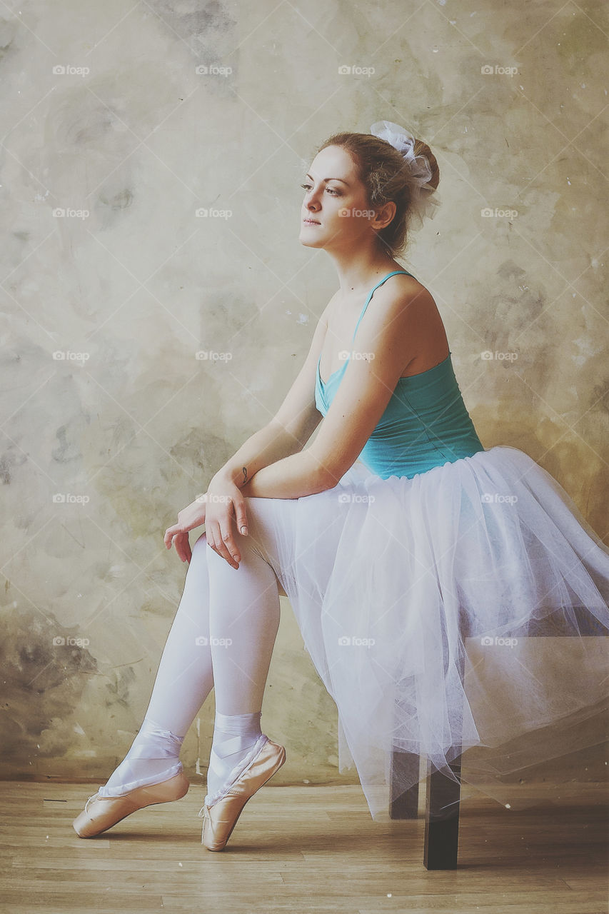 Young and graceful ballerina in pointe shoes and a tutu dances in the studio. Choreography and dancing classes concept.