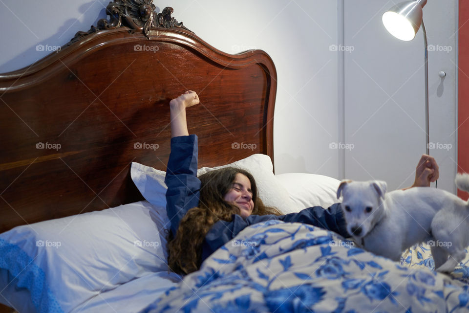 Girl with her dog stretching in bed